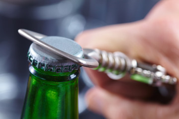 A hand opening a bottle of beer