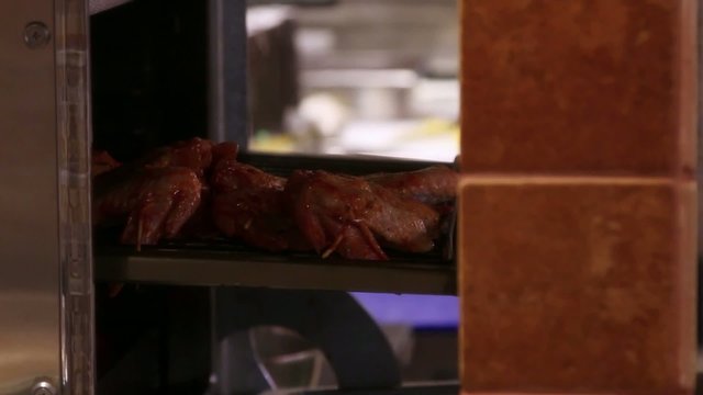 chef puts meat skewers in the oven.