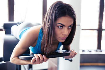 Young woman flexing back muscles on bench