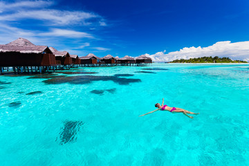 Young woman swimming from hut in tropical lagoon - obrazy, fototapety, plakaty