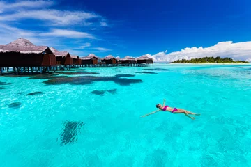 Fototapeten Young woman swimming from hut in tropical lagoon © Martin Valigursky