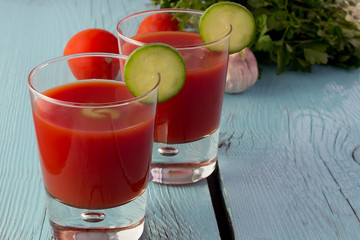Tomato gazpacho in glasses over blue wooden table