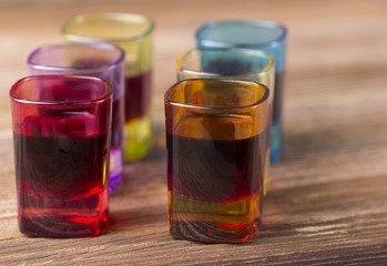 Filled coloured glasses on wooden background