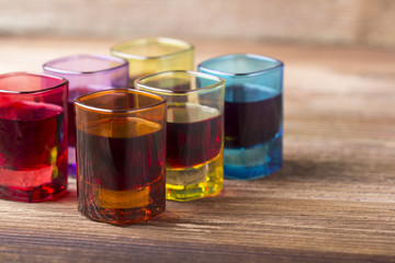 Filled coloured glasses on wooden background