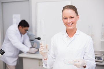 Obraz na płótnie Canvas Smiling scientist filling a petri dish
