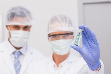 Scientists examining green precipitate in tube
