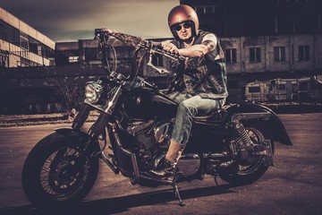 Fototapeta na wymiar Tattooed biker and his bobber style motorcycle on a city streets