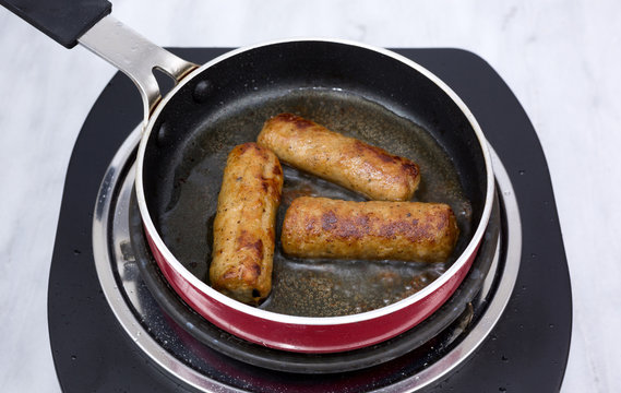 Sausages cooking in small pan