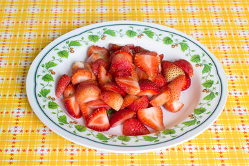 many strawberry in dish on yellow table cover