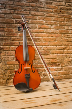 Violin and bow lean against the old brick wall