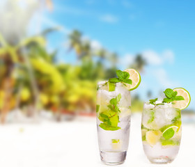 Mojito drink, Hat and flip-flops with tropical beach background,