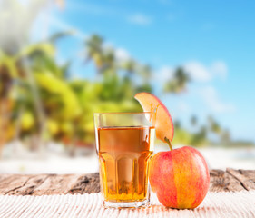 Fresh juice with fruits on wooden table, tropical beach 