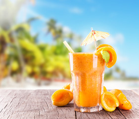 Fresh juice with fruits on wooden table, tropical beach 