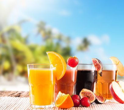 Fresh juice with fruits on wooden table, tropical beach 