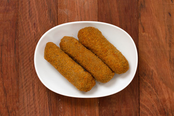 meat croquete on plate on brown background
