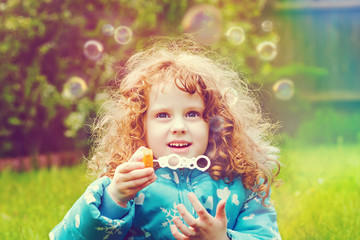 little girl blowing soap bubbles, closeup portrait beautiful cur