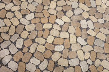 Mosaik aus ovalen grauen und braunen Pflastersteinen