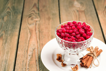 Frozen red currant berries in a glass bowl with cinnamon