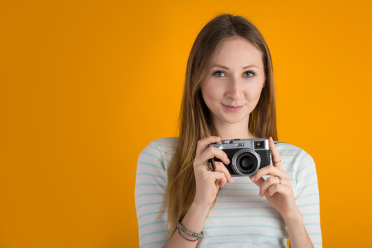 Smiling woman with vintage camera close up against orange backgr