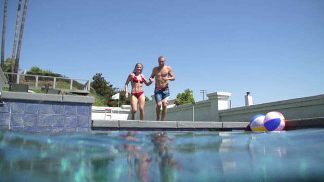 Slow Motion Couple Jumping Into Swimming Pool Holding Hands