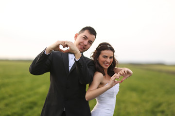 Bride and groom making love sign