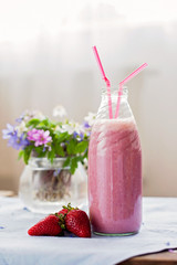 Strawberry smoothie freshly made in a jar with a lined straw, fo