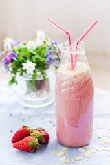 Strawberry smoothie freshly made in a jar with a lined straw, fo