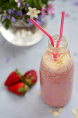 Strawberry smoothie freshly made in a jar with a lined straw