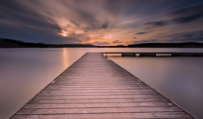 Fototapeta na wymiar Beautiful long exposure lake with jetty at sunset.