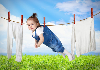 Funny child hanging on line with clothes, laundry creative conce