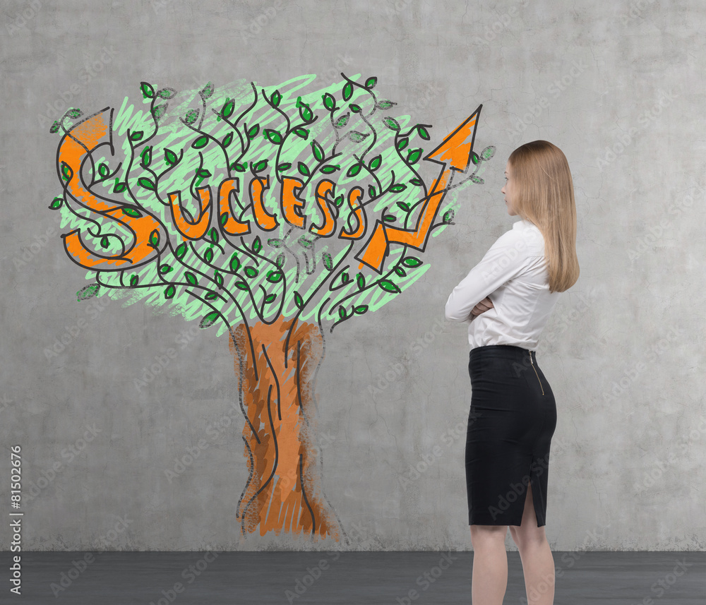 Wall mural young business woman is looking on a wall with success tree.