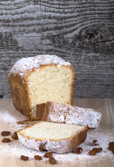 Cake with raisin and sugar powder on the wooden table. Selective