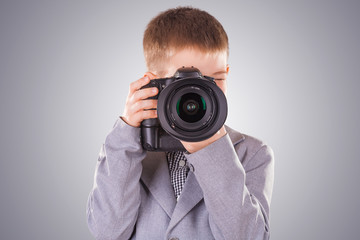 kid holding a dslr camera on a blue background