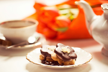 Delicious cake with coffe and tulips on table