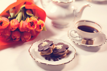 Delicious cake with coffe and tulips on table