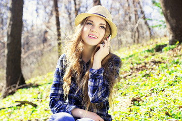 Beautiful young blonde in a hat with a phone