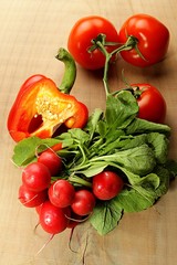bunch of radishes, tomatoes and peppers on a wooden background