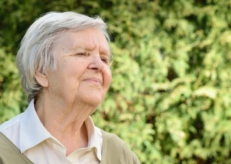 Senior woman smiling and dreaming in garden.