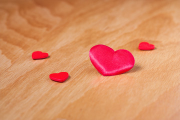 Fototapeta premium Red hearts on beige wooden surface