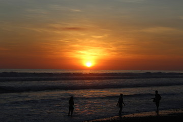 Menschen abends am Strand beim Sonnenuntergang