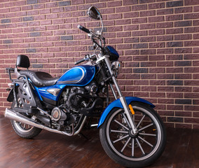 Obraz na płótnie Canvas Blue motorbike parked in front of a brick wall