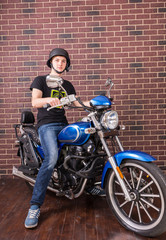 Fototapeta na wymiar Young Man on Motorcycle in front of Brick Wall