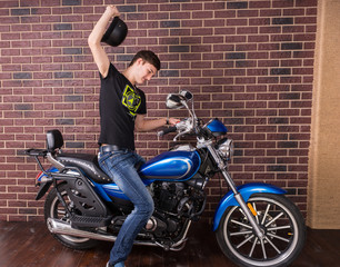 Obraz na płótnie Canvas Man on a Motorbike Raising his Black Helmet