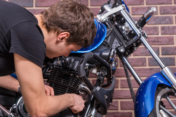 Close up Young Man Fixing his Blue Motorcycle