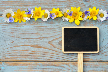 wooden background with chalk board and fieldflowerss