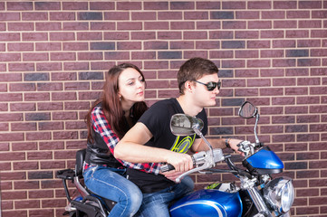 Obraz na płótnie Canvas Young Couple on Motorcycle in front of Brick Wall