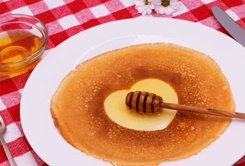 Pancakes heart with honey, flower and cutlery