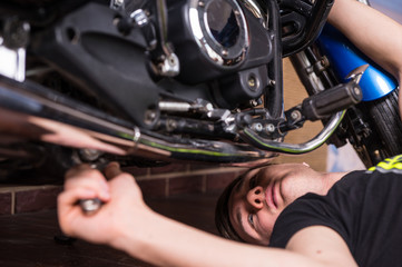 Fototapeta na wymiar Young man doing maintenance on his motorbike