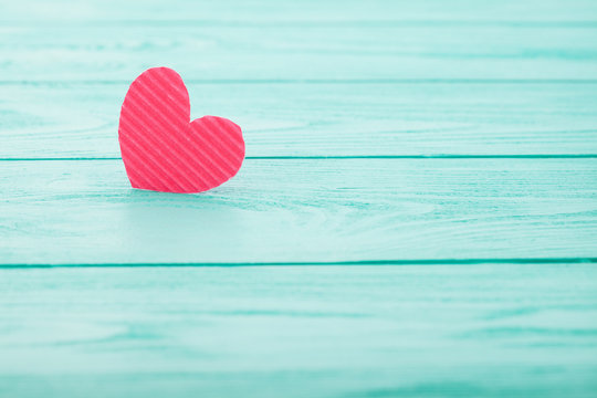 Pink heart on blue wooden background. Selective focus
