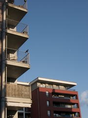Moderne Wohnhäuser mit Balkons und Penthouse vor blauem Himmel im Sonnenschein am Osthafen im...